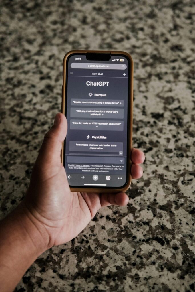 Hand holding a smartphone showing the ChatGPT app above a stone benchtop