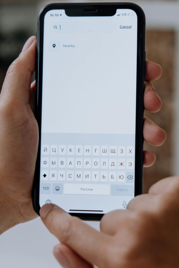 Hands holding a smartphone and typing into a search bar