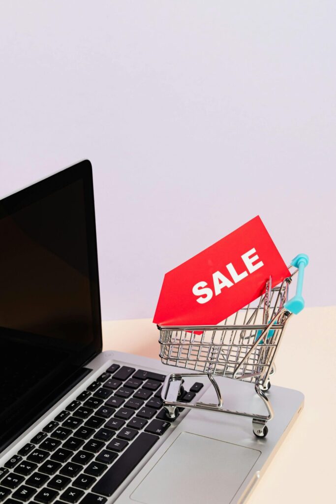 Miniature shopping trolley with a red sale tag sitting on a laptop keyboard